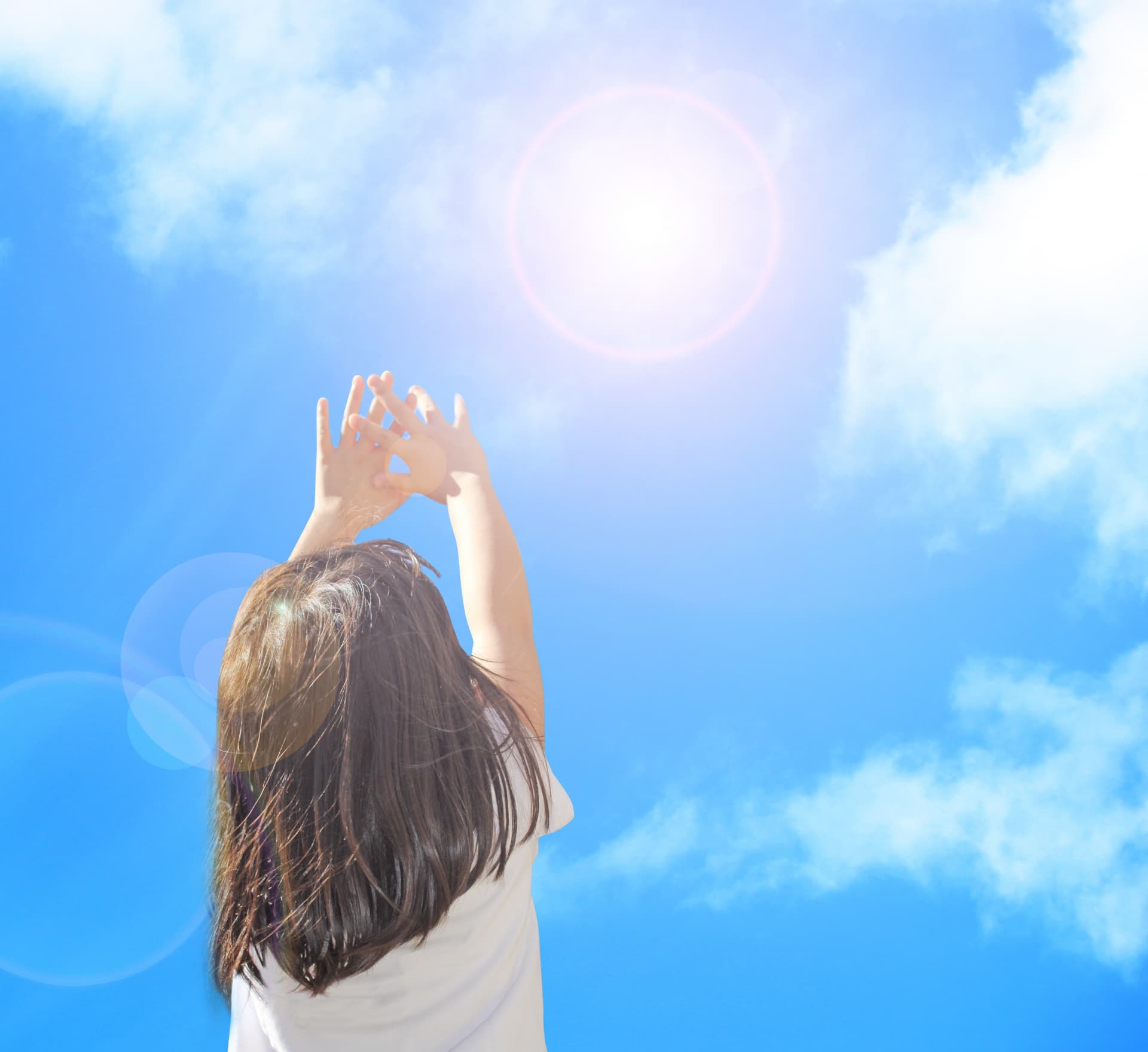 太陽に手をかざす少女